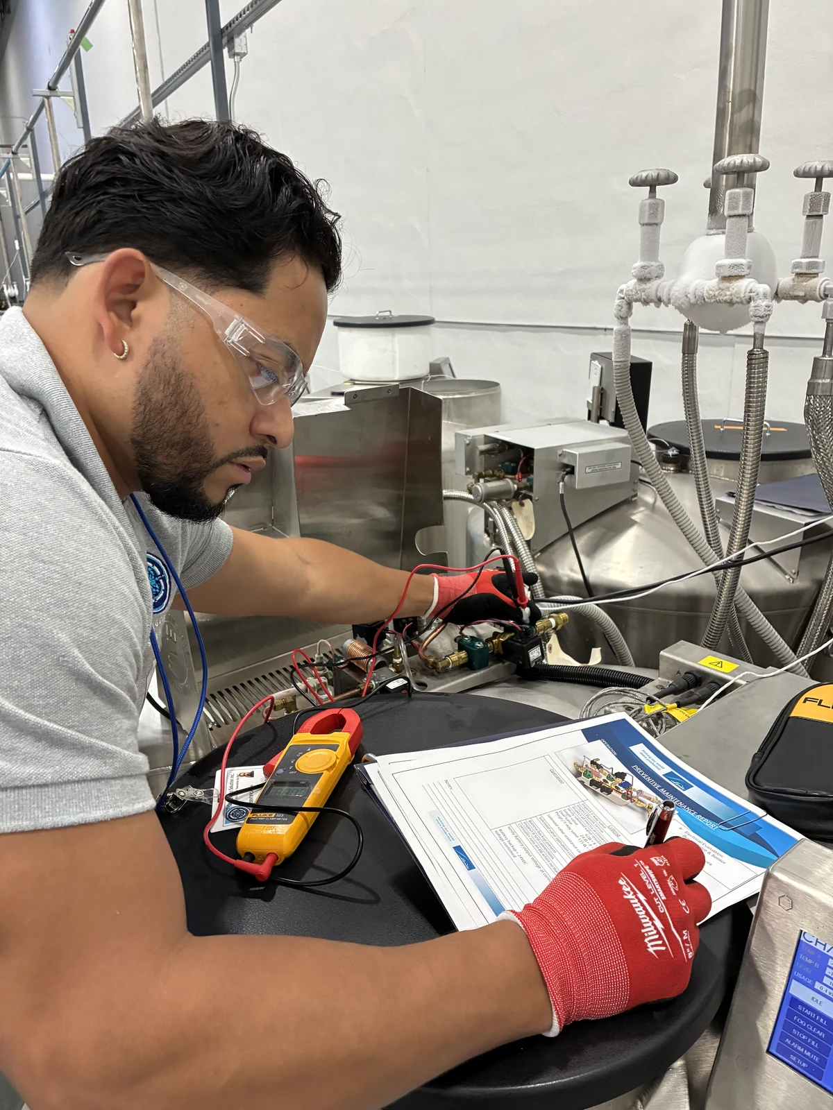 Technician testing cryogenic equipment with a multimeter